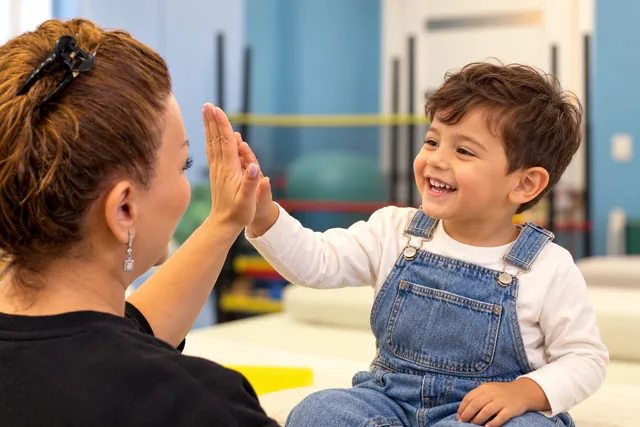 A child and educator share a cheerful high five.